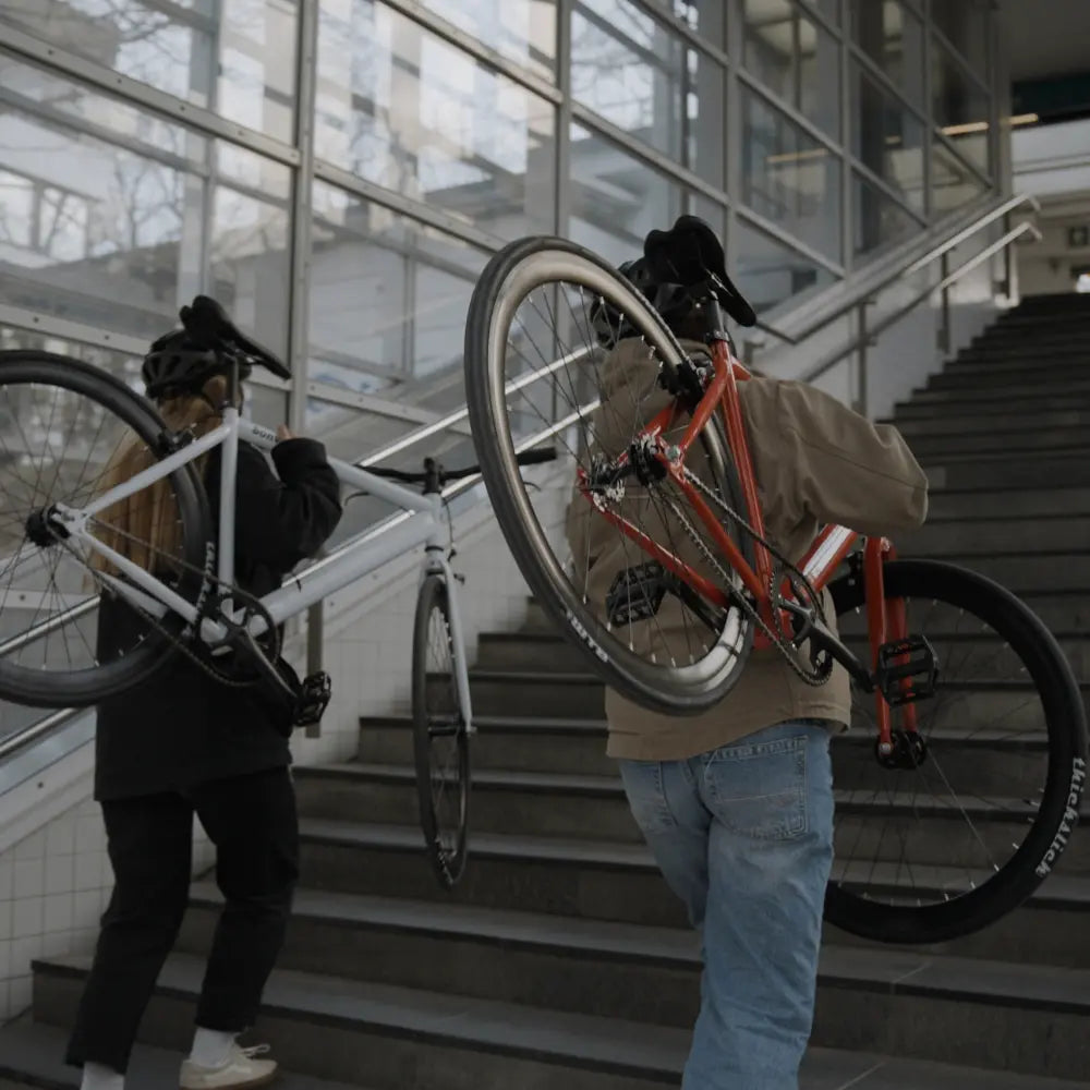 zwei Personen, die ein Bonvelo BLIZZ die Treppe hinauf tragen