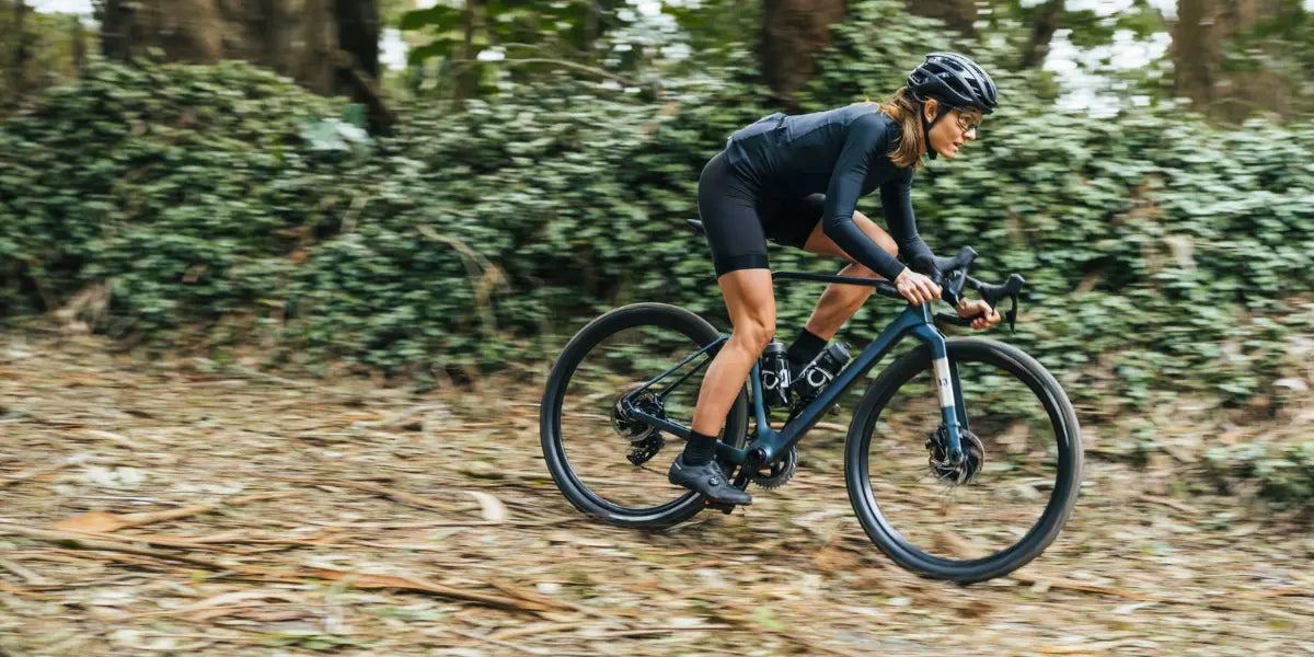 Eine Frau auf einem Gravel Bike von Rondo im Wald.